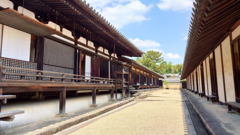 長い高床式の木造建築と、その向かいに並ぶ建物の間の砂利道