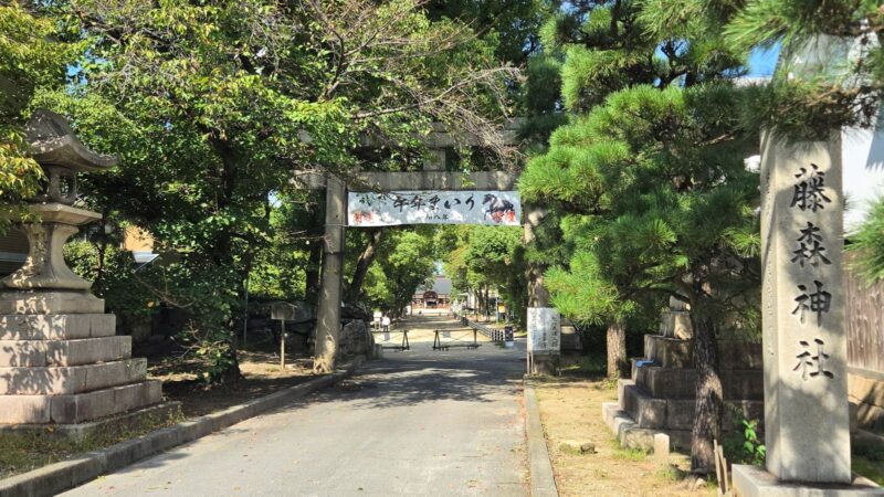 藤森神社の参道入口に立つ鳥居と、本殿へ向かってまっすぐ伸びる緑豊かな参道。
